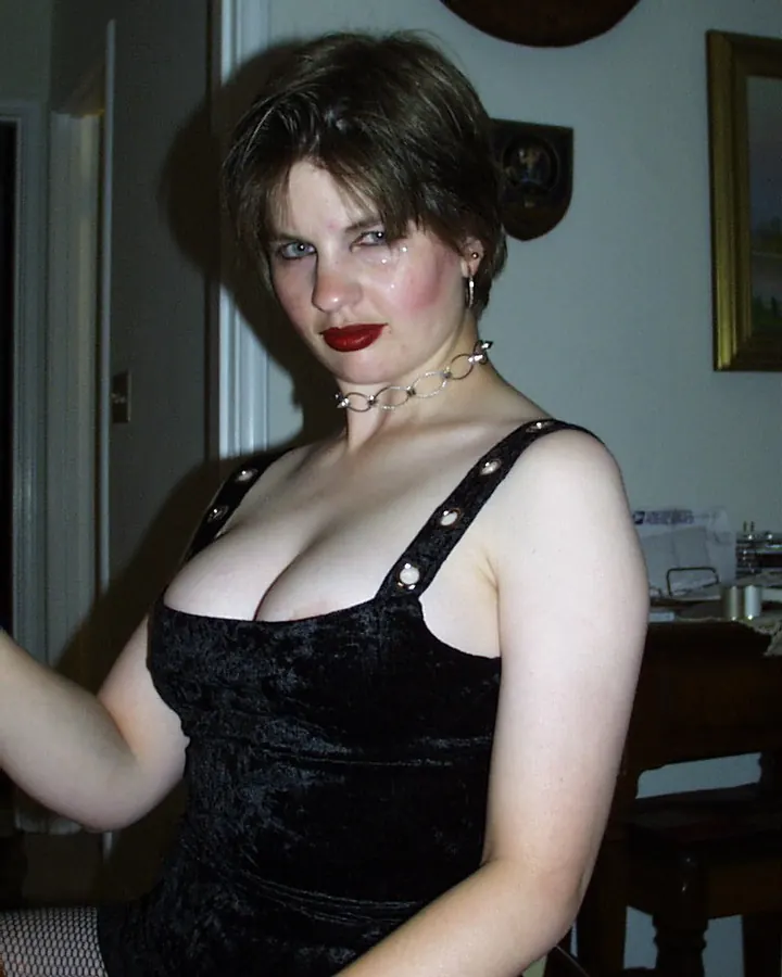 Femme aux cheveux blonds, en robe noire, souriante, posant dans une cuisine